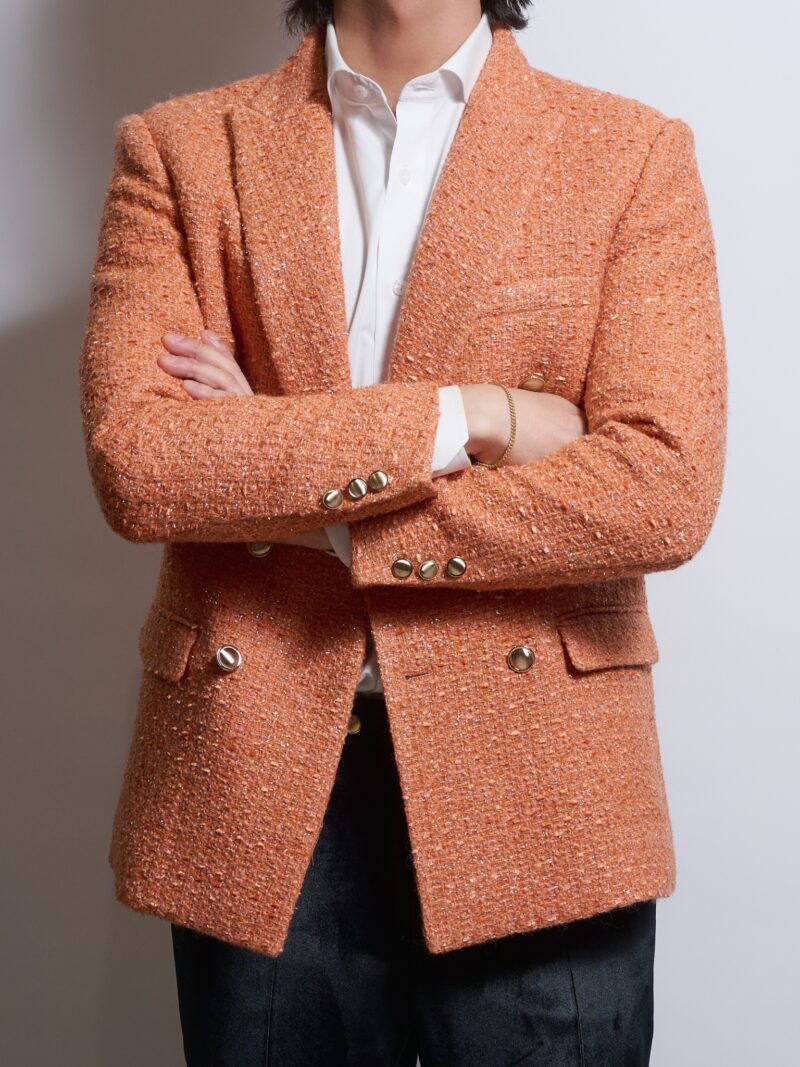 オレンジブレークツイードラメダブルジャケットを着る男性