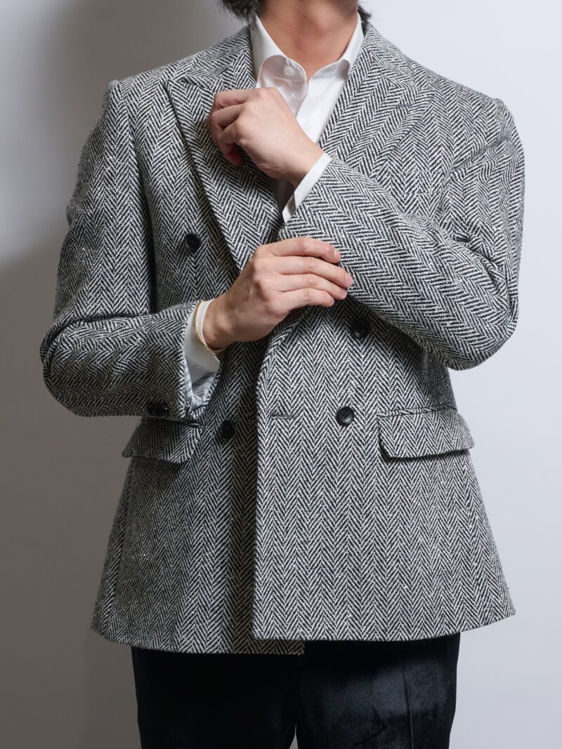 グレーヘリンボーンツイードラインストーンダブルジャケットを着る男性