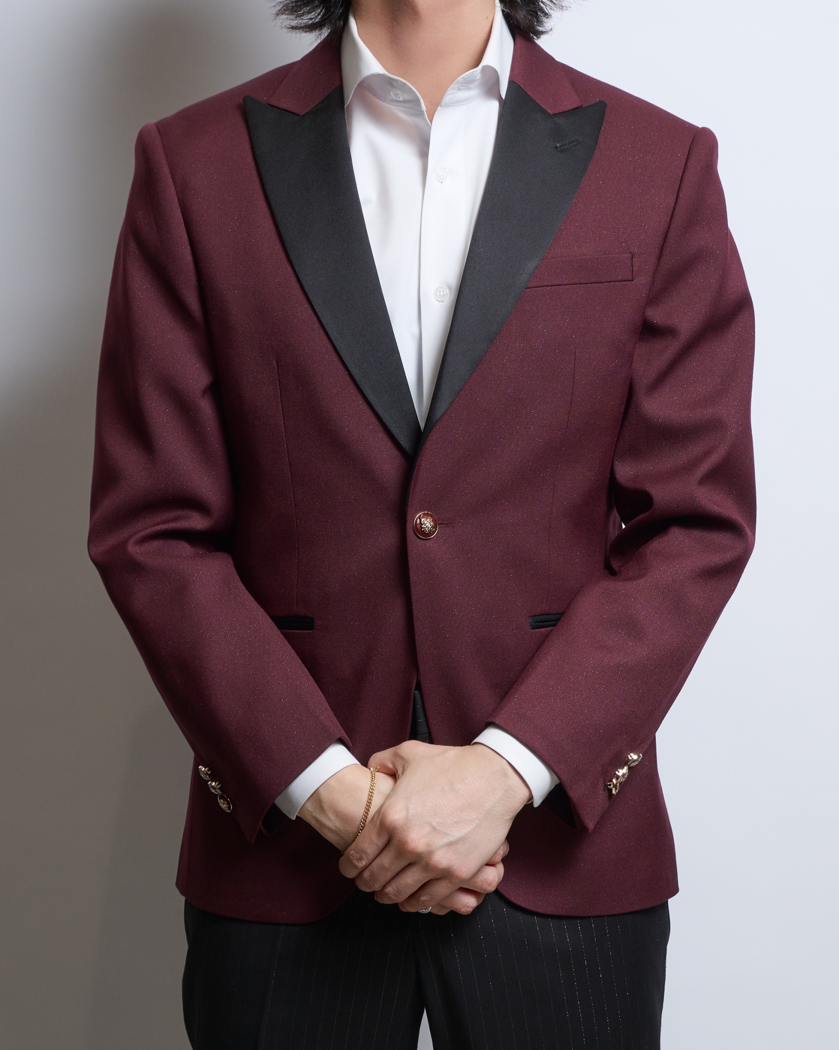 バーガンディーラメ入りシングルジャケット、襟ピークドラペル黒サテンを着る男性